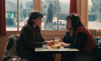 Movie still from “Vagabond” (1985), directed by Agnès Varda – Two women sitting at a table in front of each other; Medium shot, High angle