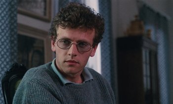 Movie still from “Vagabond” (1985), directed by Agnès Varda – A man wearing glasses and a gray sweater; Close Up shot, Over the shoulder angle