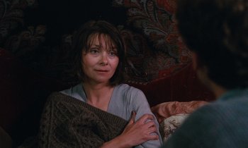 Movie still from “Vagabond” (1985), directed by Agnès Varda – A woman sitting on a couch holding a blanket; Close Up shot, Over the shoulder angle