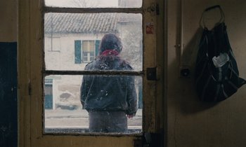 Movie still from “Vagabond” (1985), directed by Agnès Varda – A person looking out of a window in the rain; Medium shot, Over the shoulder angle