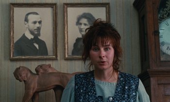 Movie still from “Vagabond” (1985), directed by Agnès Varda – A woman standing in front of a picture of a man and a dog; Close Up shot, Over the shoulder angle