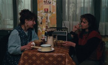 Movie still from “Vagabond” (1985), directed by Agnès Varda – Two people sitting at a table eating soup; Medium shot, High angle