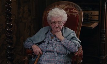 Movie still from “Vagabond” (1985), directed by Agnès Varda – An old woman sitting in a chair with her hand on her chin; Medium shot, High angle