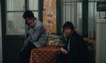 Movie still from “Vagabond” (1985), directed by Agnès Varda – A man and a woman sitting at a table; Medium shot, High angle