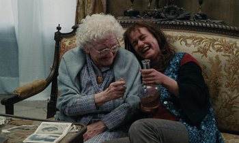 Movie still from “Vagabond” (1985), directed by Agnès Varda – An older woman and a younger woman sitting on a couch; Medium shot, High angle