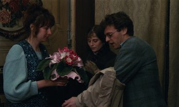 Movie still from “Vagabond” (1985), directed by Agnès Varda – Two women and a man holding a bouquet of flowers; Medium shot, Over the shoulder angle