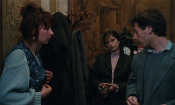 Movie still from “Vagabond” (1985), directed by Agnès Varda – A group of people standing in a room talking to each other; Medium shot, Over the shoulder angle
