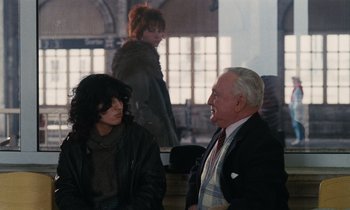 Movie still from “Vagabond” (1985), directed by Agnès Varda – A man and a woman sitting next to each other; Medium shot, Over the shoulder angle
