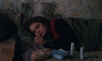 Movie still from “Vagabond” (1985), directed by Agnès Varda – A woman sleeping on a table with a bag of tissues; Medium shot, High angle