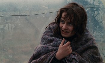 Movie still from “Vagabond” (1985), directed by Agnès Varda – A woman wrapped in a blanket looking out a window; Close Up shot, Low angle