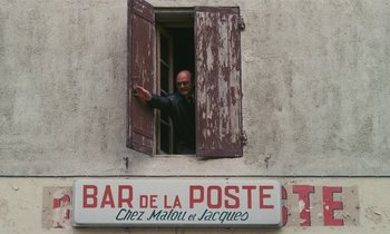 Movie still from “Vagabond” (1985), directed by Agnès Varda – A man standing at the window of a building; Wide shot, Low angle