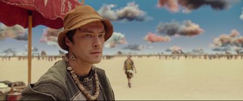 Movie still from “Valerian and the City of a Thousand Planets” (2017), directed by Luc Besson – A man in a hat and necklace standing in the desert; Close Up shot, Low angle