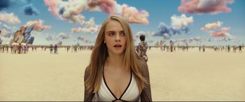 Movie still from “Valerian and the City of a Thousand Planets” (2017), directed by Luc Besson – A woman standing on a beach with a crowd of people in the background; Medium shot, Over the shoulder angle