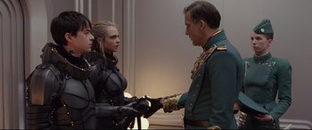 Movie still from “Valerian and the City of a Thousand Planets” (2017), directed by Luc Besson – A man and a woman are shaking hands in front of a wall; Medium shot, Over the shoulder angle