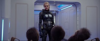 Movie still from “Valerian and the City of a Thousand Planets” (2017), directed by Luc Besson – A woman dressed in a futuristic suit holding a gun in front of a group of people; Medium shot, Over the shoulder angle