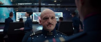 Movie still from “Valerian and the City of a Thousand Planets” (2017), directed by Luc Besson – A man with a bald head wearing a uniform; Close Up shot, Over the shoulder angle