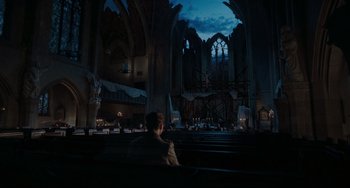 Movie still from “Valkyrie” (2008), directed by Bryan Singer – A man sitting in a pew in front of an old cathedral; Extreme Wide shot, High angle