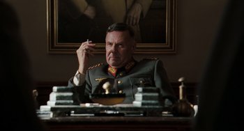Movie still from “Valkyrie” (2008), directed by Bryan Singer – An older man in a military uniform sitting at a desk; Medium shot, Low angle