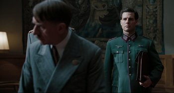 Movie still from “Valkyrie” (2008), directed by Bryan Singer – A man in a suit and a man in a green uniform; Medium shot, Over the shoulder angle