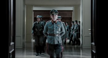 Movie still from “Valkyrie” (2008), directed by Bryan Singer – A group of men in uniforms are standing in a hallway; Medium shot, Low angle