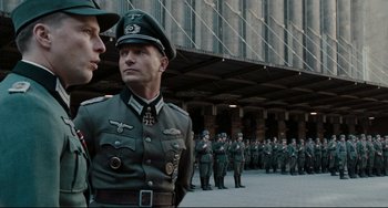 Movie still from “Valkyrie” (2008), directed by Bryan Singer – A group of men in uniforms standing next to each other; Medium shot, Over the shoulder angle