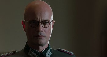Movie still from “Valkyrie” (2008), directed by Bryan Singer – A bald man wearing glasses and wearing a uniform; Close Up shot, Low angle