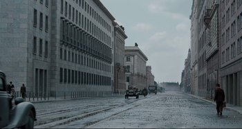 Movie still from “Valkyrie” (2008), directed by Bryan Singer – A street scene with cars parked on the side of the road; Extreme Wide shot, High angle