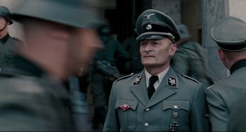 Movie still from “Valkyrie” (2008), directed by Bryan Singer – An older man in a military uniform is looking at the camera; Medium shot, Low angle