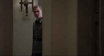 Movie still from “Valkyrie” (2008), directed by Bryan Singer – A man in a military uniform standing in a room; Medium shot, Over the shoulder angle
