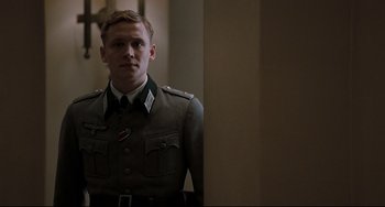 Movie still from “Valkyrie” (2008), directed by Bryan Singer – A man in a military uniform standing in front of a wall; Medium shot, Low angle