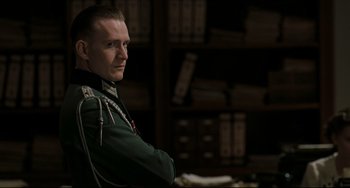 Movie still from “Valkyrie” (2008), directed by Bryan Singer – A man in a military uniform standing in front of a book shelf; Medium shot, Over the shoulder angle