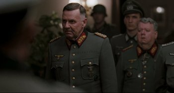Movie still from “Valkyrie” (2008), directed by Bryan Singer – A man in a military uniform standing next to another man in a uniform; Close Up shot, Over the shoulder angle