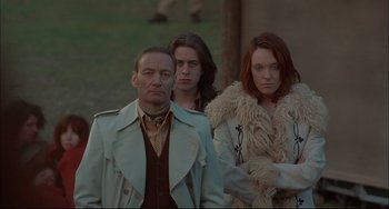 Movie still from “Velvet Goldmine” (1998), directed by Todd Haynes – A man and two women standing next to each other; Medium shot, Low angle