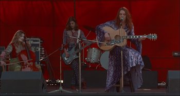 Movie still from “Velvet Goldmine” (1998), directed by Todd Haynes – A group of people that are on a stage; Wide shot, Low angle