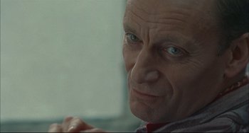 Movie still from “Velvet Goldmine” (1998), directed by Todd Haynes – An older man with a serious look on his face; Close Up shot, Over the shoulder angle