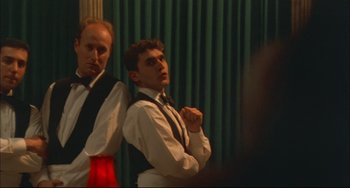 Movie still from “Velvet Goldmine” (1998), directed by Todd Haynes – Two men standing next to each other in front of a green curtain; Medium shot, Low angle