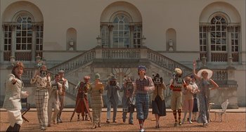 Movie still from “Velvet Goldmine” (1998), directed by Todd Haynes – A group of people taking pictures in front of a building; Wide shot, Low angle