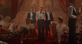 Movie still from “Velvet Goldmine” (1998), directed by Todd Haynes – A group of men and women in tuxedos standing next to each other; Wide shot, Low angle