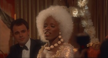 Movie still from “Velvet Goldmine” (1998), directed by Todd Haynes – A woman in a white dress with a white wig; Close Up shot, Over the shoulder angle