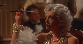 Movie still from “Velvet Goldmine” (1998), directed by Todd Haynes – A woman in a white wig holding a brush in her hand; Close Up shot, Over the shoulder angle