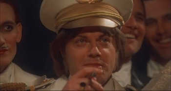 Movie still from “Velvet Goldmine” (1998), directed by Todd Haynes – A person wearing a hat and smoking a cigarette; Close Up shot, High angle