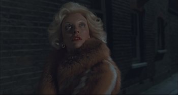 Movie still from “Velvet Goldmine” (1998), directed by Todd Haynes – A woman with blonde hair wearing a fur coat; Close Up shot, Low angle
