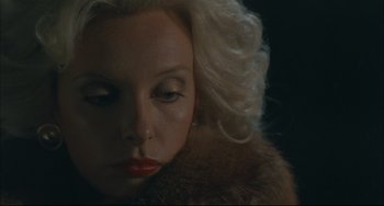 Movie still from “Velvet Goldmine” (1998), directed by Todd Haynes – A woman with blonde hair wearing a fur coat; Close Up shot, High angle