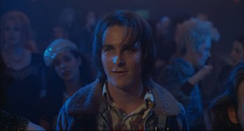 Movie still from “Velvet Goldmine” (1998), directed by Todd Haynes – A man in a crowd of onlookers at a party; Close Up shot, Low angle