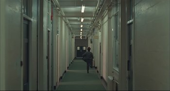 Movie still from “Velvet Goldmine” (1998), directed by Todd Haynes – A person walking down a long hallway in a building; Extreme Wide shot, High angle