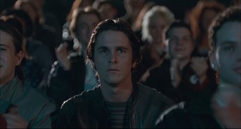 Movie still from “Velvet Goldmine” (1998), directed by Todd Haynes – A man in a crowd of people is looking into the camera; Close Up shot, Over the shoulder angle