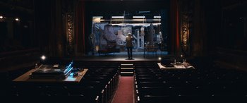 Movie still from “Venus in Fur” (2013), directed by Roman Polanski – A man standing in front of a stage with chairs; Extreme Wide shot, High angle