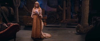 Movie still from “Venus in Fur” (2013), directed by Roman Polanski – A woman dressed in a long dress standing on a stage holding a book; Wide shot, High angle