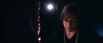 Movie still from “Venus in Fur” (2013), directed by Roman Polanski – A man wearing glasses standing in front of a light; Close Up shot, Over the shoulder angle