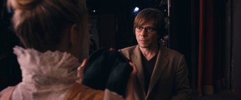 Movie still from “Venus in Fur” (2013), directed by Roman Polanski – A man wearing glasses and a brown jacket looking into a mirror; Medium shot, Over the shoulder angle